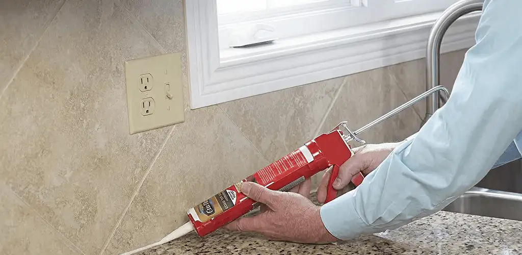 Handyman applying caulk along a kitchen backsplash and countertop seam in Jersey City, NJ