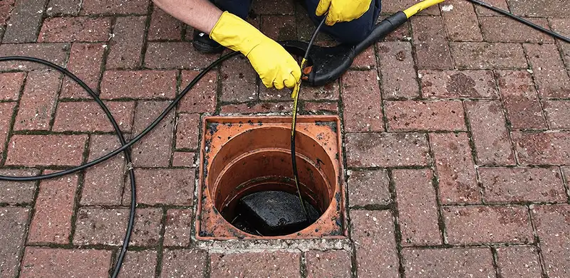Drain cleaning technician using a drain snake to clear a clogged drain in Jersey City, NJ
