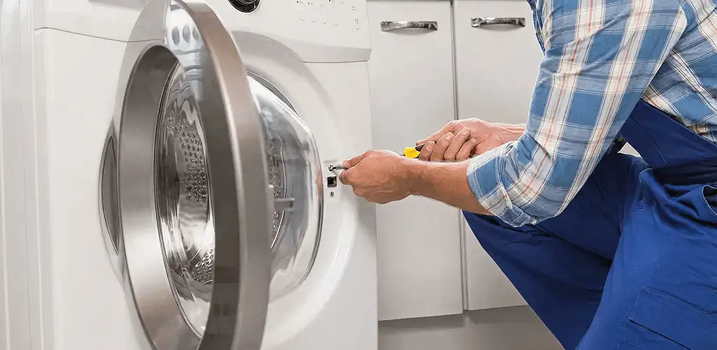 Handyman repairing a clothes dryer and checking electrical connections in Jersey City, NJ
