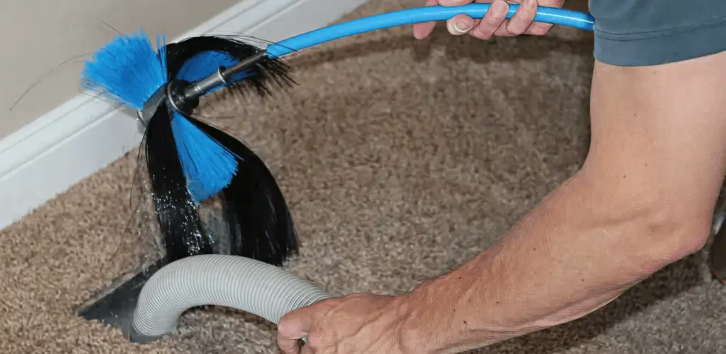 Dryer vent cleaning technician brushing lint from a vent line in Jersey City, NJ
