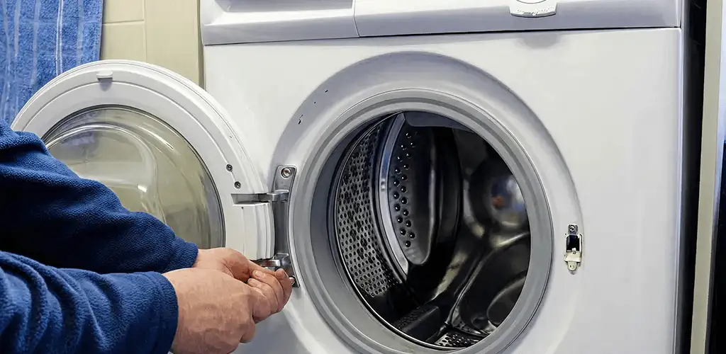 Washing machine repair handyman checking a front-load washer door and latch in Jersey City, NJ