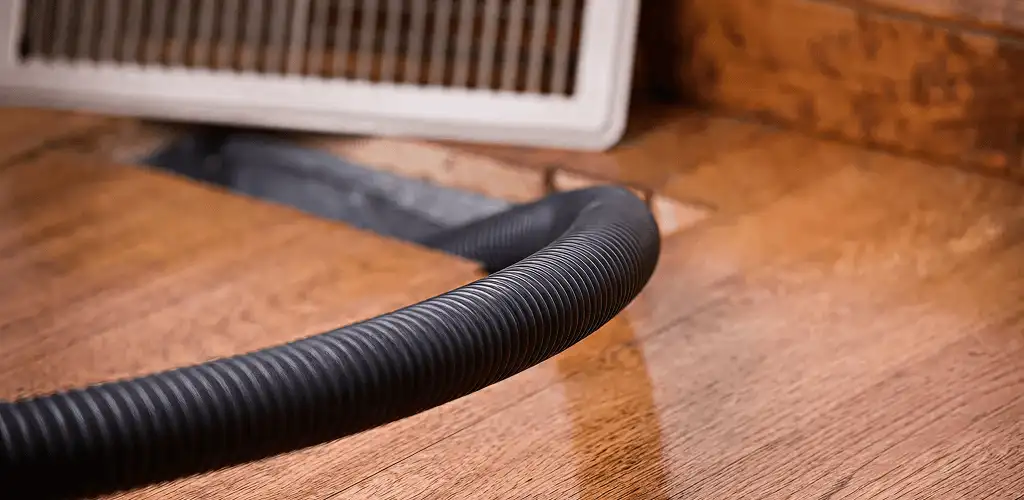 Air duct cleaning hose inserted into a floor vent for ductwork cleaning in Jersey City, NJ