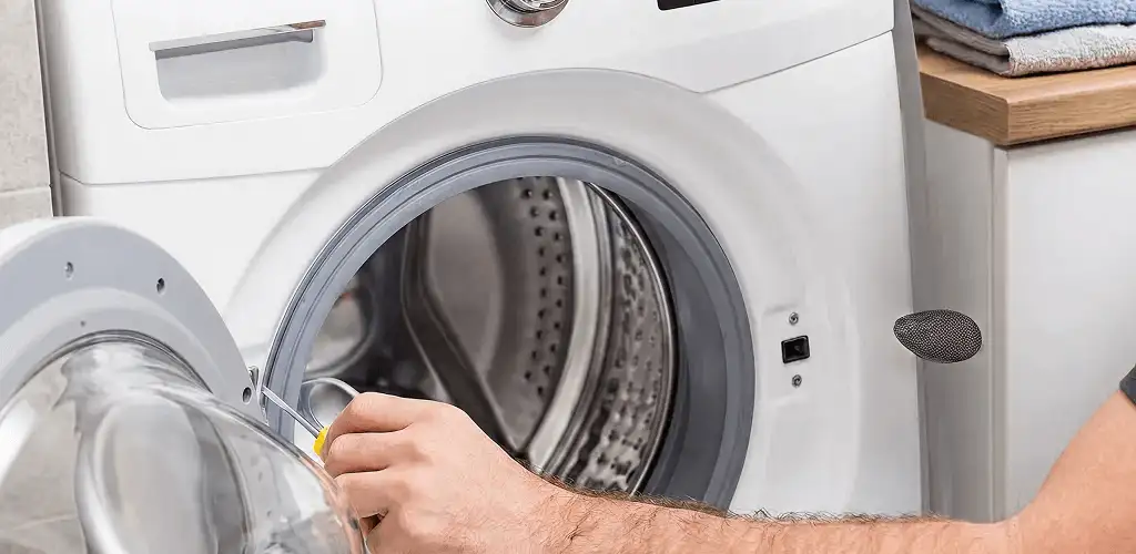 Handyman repairing a front-load washing machine and inspecting the drum in Jersey City, NJ