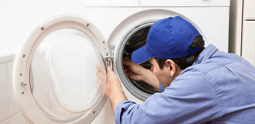 Washing machine repair handyman inspecting a front-load washer drum in Jersey City, NJ
