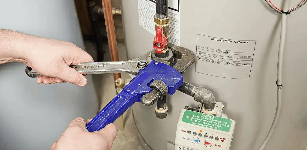 Water heater repair technician tightening the shutoff valve and supply line in Jersey City, NJ